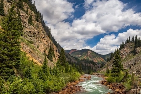 Whether in the San Juan Mountains or anywhere you find your rhythm, consistent nourishment supports the energy and resilience needed for an active, purposeful life. Lush mountain valley, near Durango, CO with a flowing river, evergreen trees, and dramatic rock faces under a bright sky — evoking the connection between nature, movement, and nourishment.